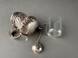 a silver teapot and a glass on a table