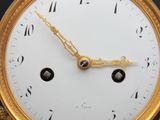 a gold clock with a white face on a black background