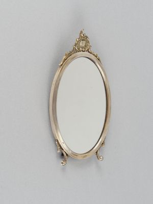 un miroir ovale fixé au mur, avec un cadre doré