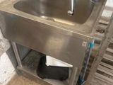 a sink in the corner of a room with a trash can