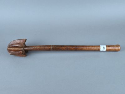 une vieille pipe en bois avec un manche en bois posée sur une surface grise