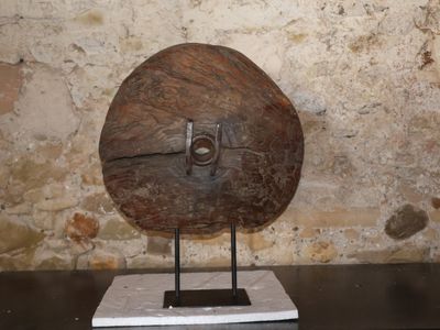 un grand objet en bois posé sur un socle devant un mur de pierre
