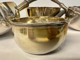a silver bowl with spoons in it sitting on a table