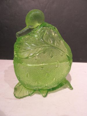 un récipient en verre vert muni d'un couvercle, posé sur une table