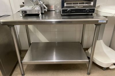 une table en acier inoxydable sur laquelle se trouvent un grille-pain et un autre grille-pain