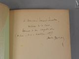 un livre ouvert, sur lequel est inscrit un poème manuscrit, posé sur une table