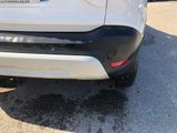 the rear end of a white car parked in a parking lot