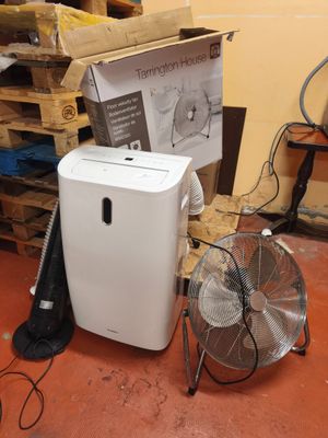 un climatiseur blanc posé à côté d'un ventilateur dans une pièce