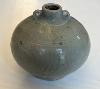 un vase vert posé sur une table recouverte d'une nappe blanche