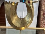 brass sculpture of a bird with a fan on top of a glass table