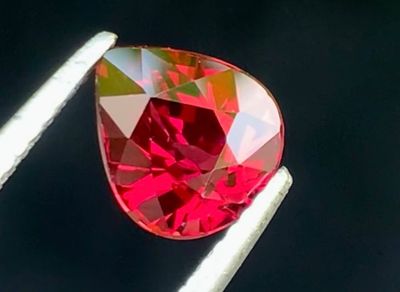 un gros plan d'un diamant rouge tenu par une pince