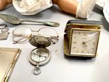 a doll sitting next to a table with a clock and other items
