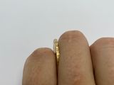 a person ' s hand holding a gold ring on a white surface