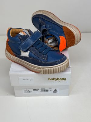 blue baby shoes with orange soles on top of a white box