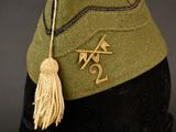 a green hat with a tassel on top of a mannequin head