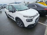une voiture blanche garée sur un parking, avec d'autres voitures en arrière-plan