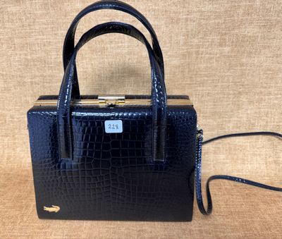 un sac à main en cuir de crocodile noir, muni d'un fermoir doré sur la poignée