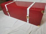 une boîte rouge bordée de blanc, posée sur un lit