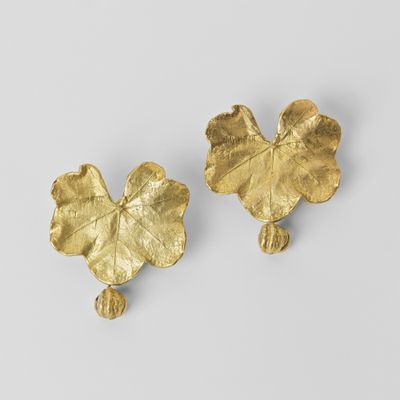 une paire de boucles d'oreilles en feuille d'or sur fond blanc