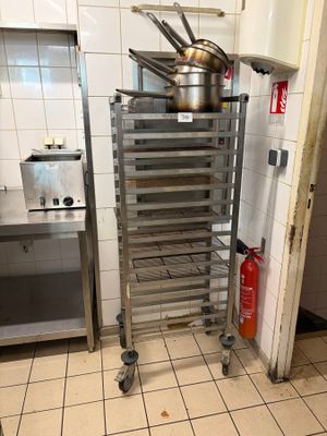 une étagère métallique sur laquelle sont posées des casseroles et des poêles, dans une cuisine