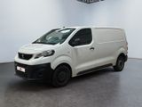La camionnette blanche est garée dans une grande pièce équipée d'un ventilateur de plafond.