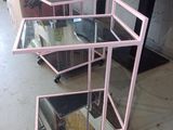 a pink cart with three glass shelves on top of it
