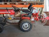 un tracteur rouge garé dans un garage, équipé d'une charrue
