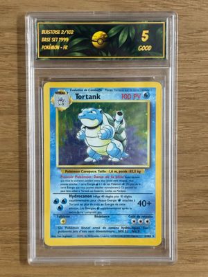 une carte Pokémon dans un étui en plastique transparent posé sur une table en bois