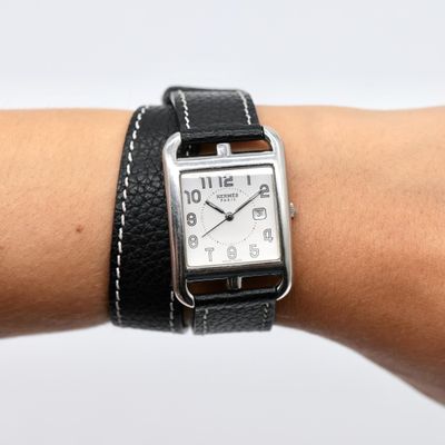 someone is wearing a watch on their wrist with a leather band