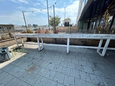 un banc blanc posé sur une terrasse, à côté d'une poubelle