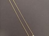 un collier avec une pendentif sur lequel est inscrit « e k »