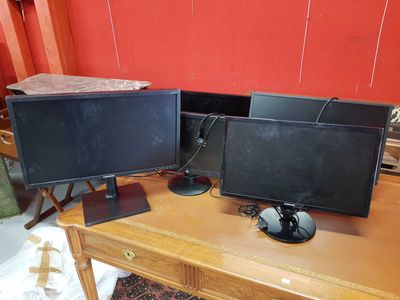 two computer monitors sitting on a desk with a red wall in the background