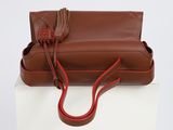 brown and red handbag with tassels on white box