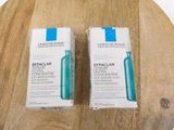 two bottles of la rochenda effaclar serum sitting on a wooden cutting board