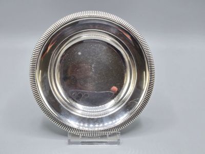 une assiette en argent posée sur un socle, avec un point rouge au centre