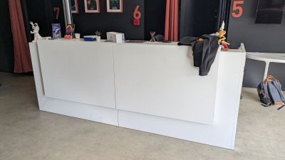 un comptoir d'accueil blanc dans une pièce où sont accrochés des tableaux aux murs