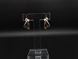 une paire de boucles d'oreilles en or et en argent posée sur un présentoir transparent
