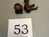 a small clock and a small figurine sitting on a table