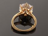 a gold ring with a white diamond on top of a black surface