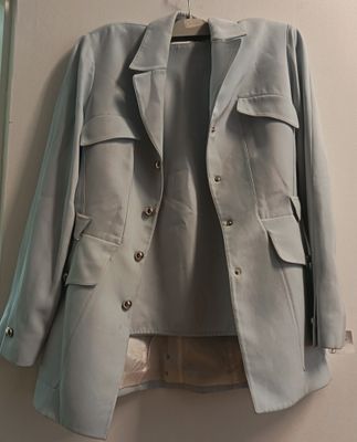 une veste grise suspendue à un cintre accroché au mur