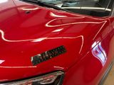 a close up of a red car with a sticker on the hood