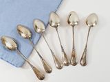 six silver spoons and a blue napkin on a white surface