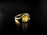 a close up of a yellow sapphire ring on a black surface