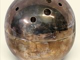 un objet métallique percé de trous, posé sur une surface blanche