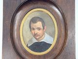 portrait d'un homme vêtu d'une chemise noire et blanche, dans un cadre en bois