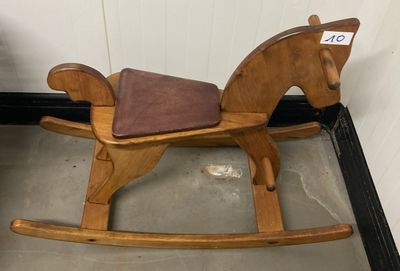 un cheval à bascule en bois avec une selle marron dans une pièce