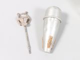 a silver cup and a metal spoon on a white surface