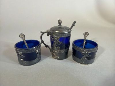 three silver and blue glass cups with spoons on a white surface