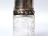 a small glass jar with a silver lid on a white surface