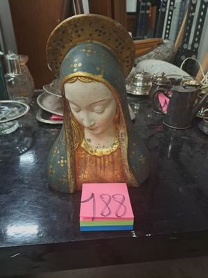 une statue de la Vierge Marie posée sur une table, avec un mot posé dessus